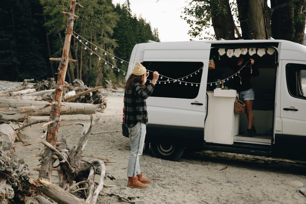 Van stationné en forêt avec une guirlande lumineuse