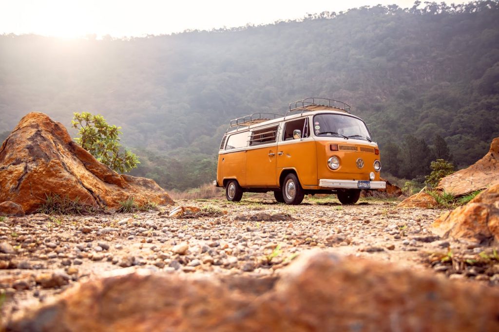 Van ancien orange stationné sur un terrain caillouteux