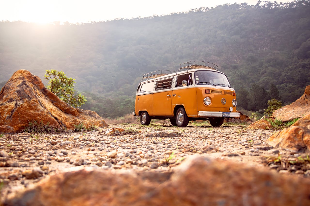Van ancien orange stationné sur un terrain caillouteux